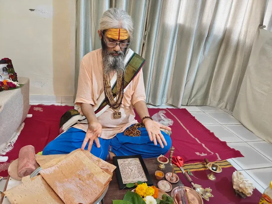A photo of Sri Damodar Dasji Maharaj performing the consecration (Puja) of the Yantra, perhaps offering flowers and water.