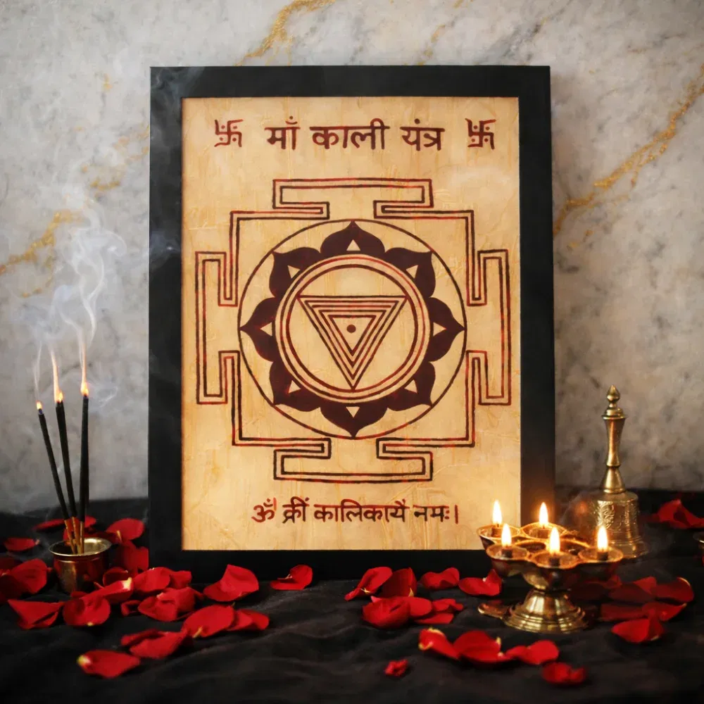 Authentic Ma Kali Yantra hand-drawn on Bhojpatra with the Beej Mantra 'Om Krim Kalikaye Namah', surrounded by red rose petals, a brass bell, and a multi-wick oil lamp.